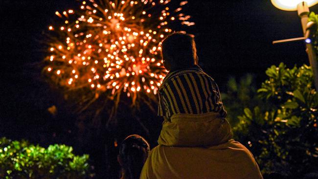 A young fella catches Darwin's New Year's Eve 2024 fireworks show on dad's shoulders at the Waterfront Precinct. Picture: Alex Treacy