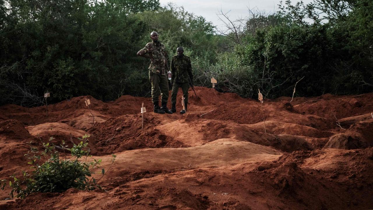 Security officers stand next to holes after exhuming bodies at the mass-grave site in Shakahola. Picture: Yasuyoshi Chiba/AFP