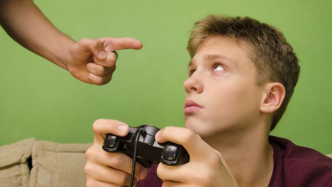 Parent schooling his kid not to play video games. Kid with sad face looking up. Picture: Istock