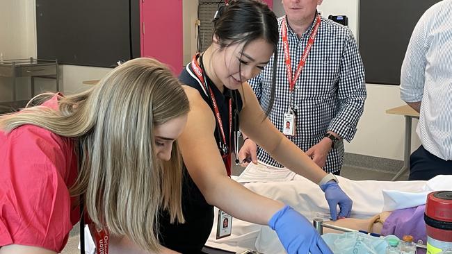 Kate and Jacqueline draw blood from the test dummy in a medical exercise. Photo: Fergus Gregg