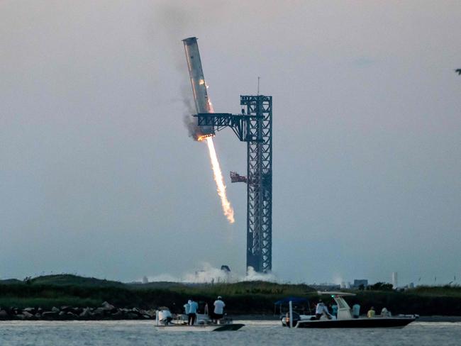 Starship's Super Heavy Booster is grappled at the launch pad in Starbase near Boca Chica, Texas, on October 13, 2024, during the Starship Flight 5 test. SpaceX successfully "caught" the first-stage booster of its Starship megarocket Sunday as it returned to the launch pad after a test flight, a world first in the company's quest for rapid reusability. (Photo by SERGIO FLORES / AFP)