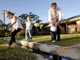 Health concerns: Water with high levels of faecal coliforms and hatching mosquito larvae lies stagnant in a stormwater drain at Evans Head. Jon Lawrence wants something done to fix the problem so his grandchildren (from left) Sophie, 6, William, 4, and Jacob Laing, 20 months, can play safely in his yard. Picture: David Nielsen