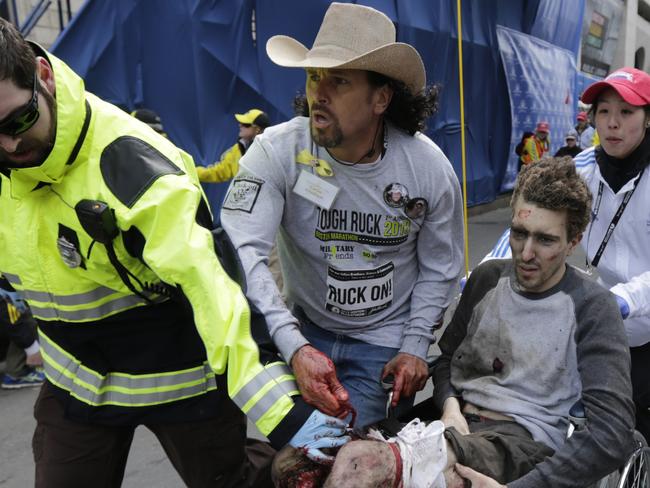 Aemergency responder and volunteers, including Carlos Arredondo, in the cowboy hat, push Jeff Bauman in a wheel chair after he was injured in an explosion near the finish line of the Boston Marathon. =