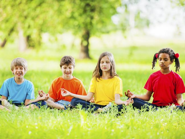 Group of kids exercising yoga in park surrounded by beautiful greenery. [