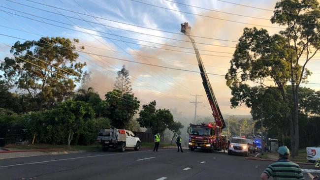 Neighbours look on as fireys in a 12m crane hose down the blaze on Plantain Rd at Shailer Park. PHOTO: Jeni Faulkner