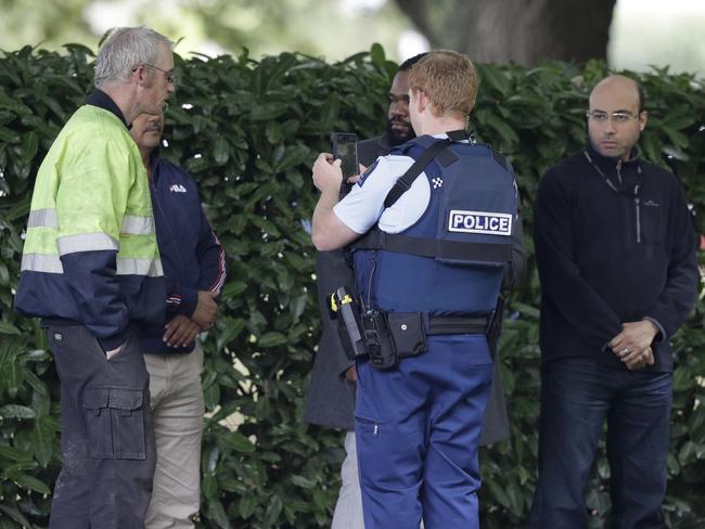 A police officer photographs witnesses near a mosque in central Christchurch. Picture: AP