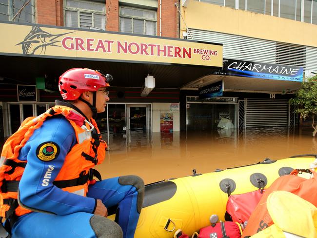 A SES volunteer steers a boat down a street. Picture: Nathan Edwards