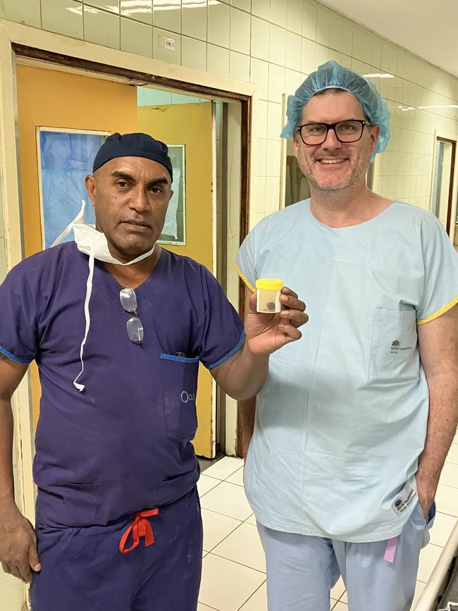 Dr Tait and Dr Olangi holding a pot containing a tumour removed from a 12-year-old patient. Picture: Ian Seppelt