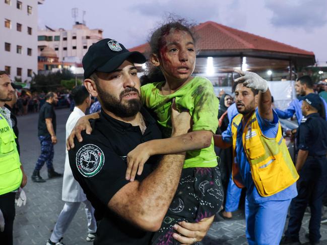 A member of the Palestinian security forces carries a child, wounded by Israeli airstrikes, into Al-Shifa hospital in Gaza City. Picture: AFP