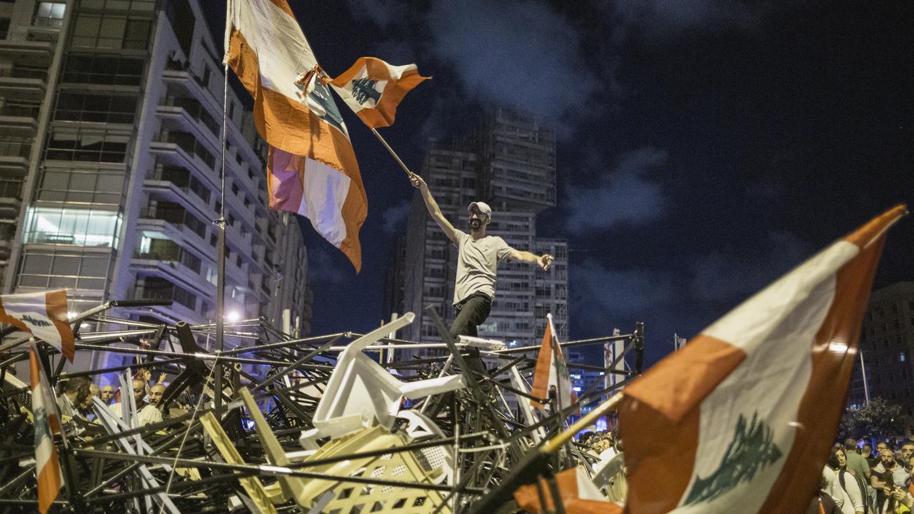 An anti-government protester waves a Lebanese flag as he stands on top of a pile of broken tents in Martyrs' Square on October 29, 2019 in Beirut, Lebanon. Picture: Getty Images