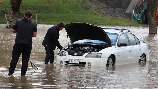 Two men and their submerged car after trying to cross the flooded Whittakers Rd rail underpass on Saturday. Picture: David Caird