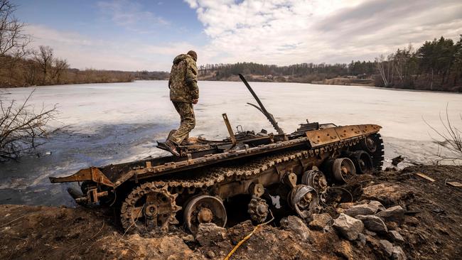 A Ukrainian serviceman stands near a destroyed Russian tank in Trostianets. Picture: AFP