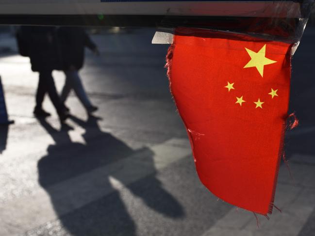 A Chinese national flag hangs from a barrier in a car park in Beijing on January 18, 2018. China's economy grew a forecast-beating 6.9 percent in 2017, picking up steam for the first time since 2010 despite its battles against a massive debt and polluting factories, official data showed on January 18. / AFP PHOTO / Greg Baker