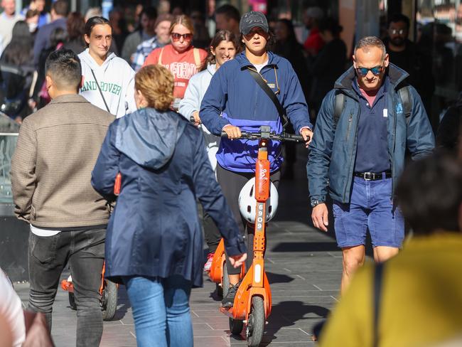 People ride e-Scooters along the footpath on Elizabeth St. Picture: Brendan Beckett