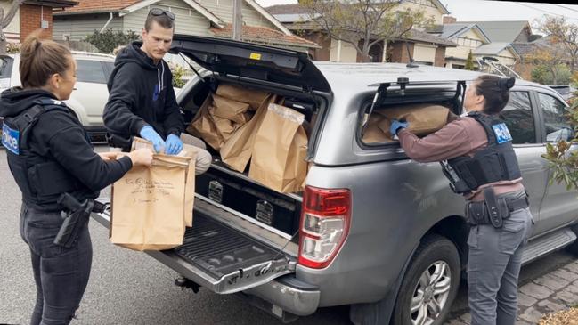 Detectives load evidence bags into the waiting station wagon. Picture: Supplied