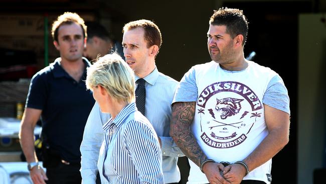 Police lead away Joshua Thornbury (right) after his home was raided in 2014. Picture: David Clark