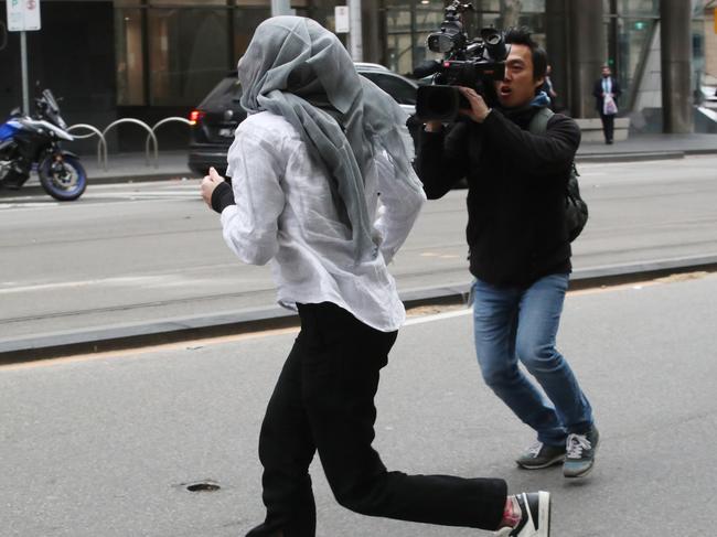 Tyler Garth, 25, covers her face from waiting media as she made her first appearance at the Melbourne Magistrates Court on 292 charges. Picture: David Crosling