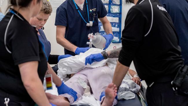 Staff hold down the arms and legs of the woman to stop her fighting them. Picture: Jake Nowakowski