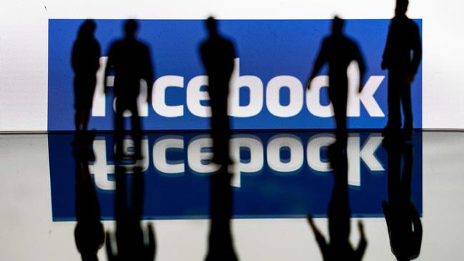 Silhouettes are seen in front of the logo of US social media Facebook. Picture: Kenzo Tribouillard/AFP