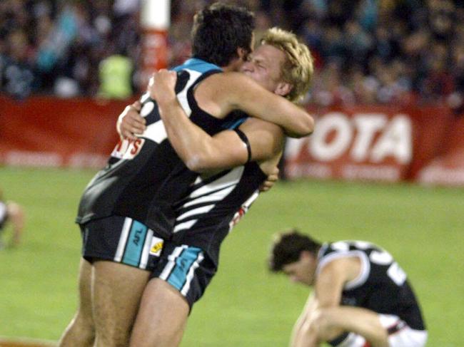 A dejected Robert Harvey in the background as Port players Roger James and Chad Cornes celebrate their win.