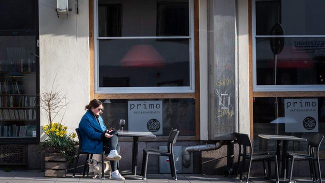 A woman has a glass of wine as she sits at the tables outside a restaurant in Stockholm, Sweden April 17, 2020 during the coronavirus COVID-19 pandemic. (Photo by Stina STJERNKVIST / various sources / AFP) / Sweden OUT