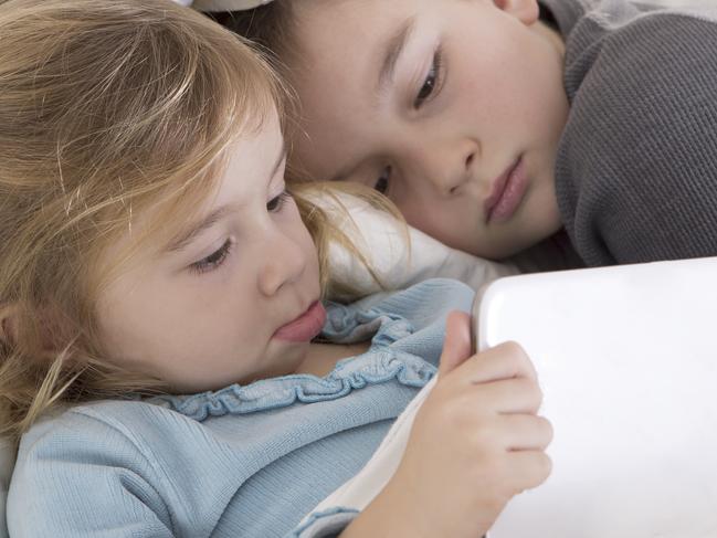 Cute little girl and boy reading on a Ipad tablet