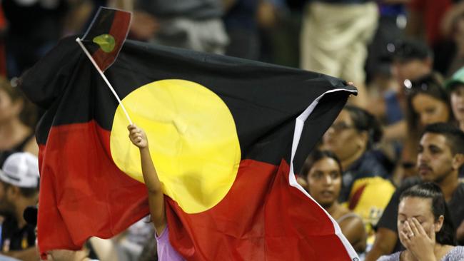 A young Indigenous All Stars fan waves two flags during the NRL Indigenous All Stars vs. World All Stars match at McDonald Jones Stadium.
