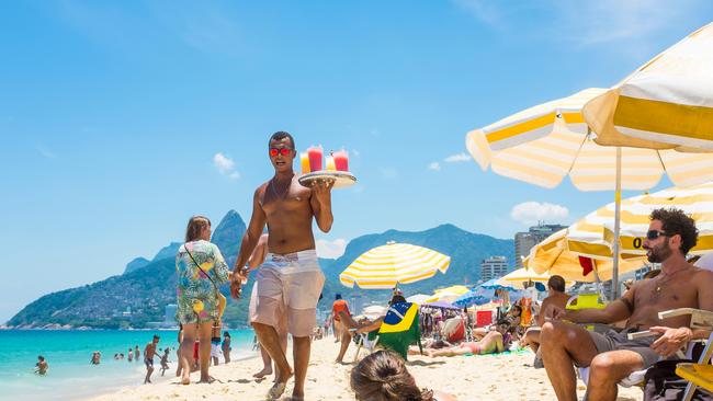 Beach vendors work the sands in the midday sun on Ipanema Beach.