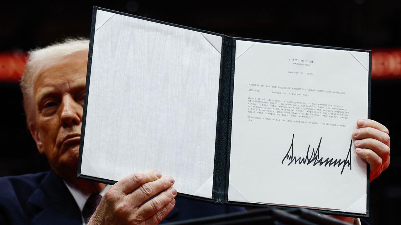 Donald Trump holds up an executive order after signing it during an indoor inauguration parade at Capital One Arena.