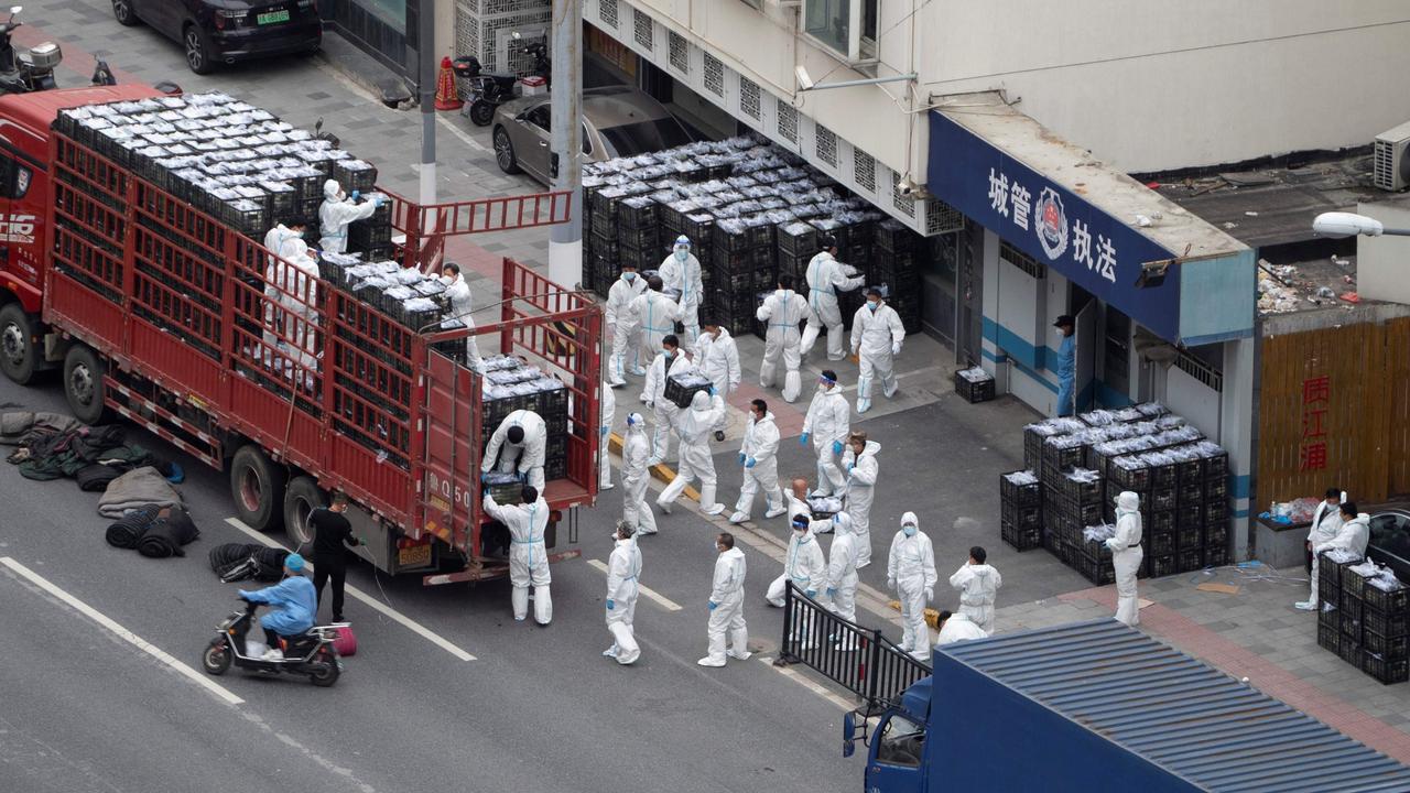 People wearing personal protective equipment as they transfer daily food supplies and necessities for local residents in lockdown in Shanghai. Picture: AFP/China OUT