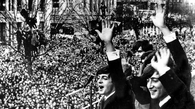 Paul McCartney (left), George Harrison and John Lennon of The Beatles wave to the massive crowd of fans gathered in Melbourne from the Southern Cross Hotel balcony, in June 1964. Picture: archive