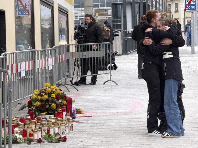 People mourn at a makeshift memorial of candles and flowers placed at the site where a man randomly attacked passers-by with a knife in Villach, Austria. Picture: AFP