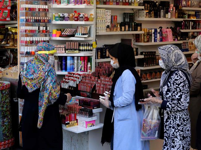 Iranians wearing protective gear amid the COVID-19 pandemic, queue to pay at a shop outside of the Grand Bazaar market in the capital Tehran, on April 18, 2020. - Iran allowed some shuttered Tehran businesses to reopen on April 18, despite the Middle East's deadliest coronavirus outbreak, as many faced a bitter choice between risking infection and economic ruin. (Photo by ATTA KENARE / AFP)