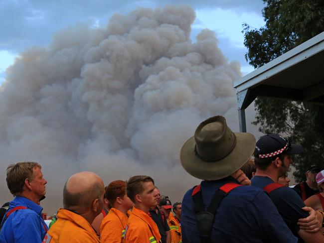 CFA members are briefed as the bushfire burns close by. Picture: Mark Stewart