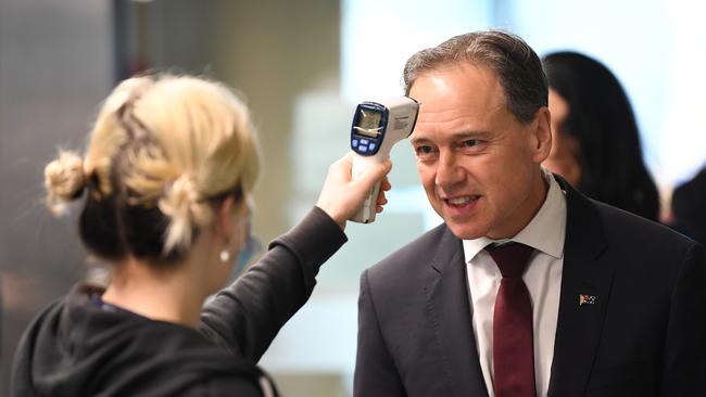 Federal Health Minister Greg Hunt has his temperature checked before touring the Royal Melbourne Hospital in Melbourne.