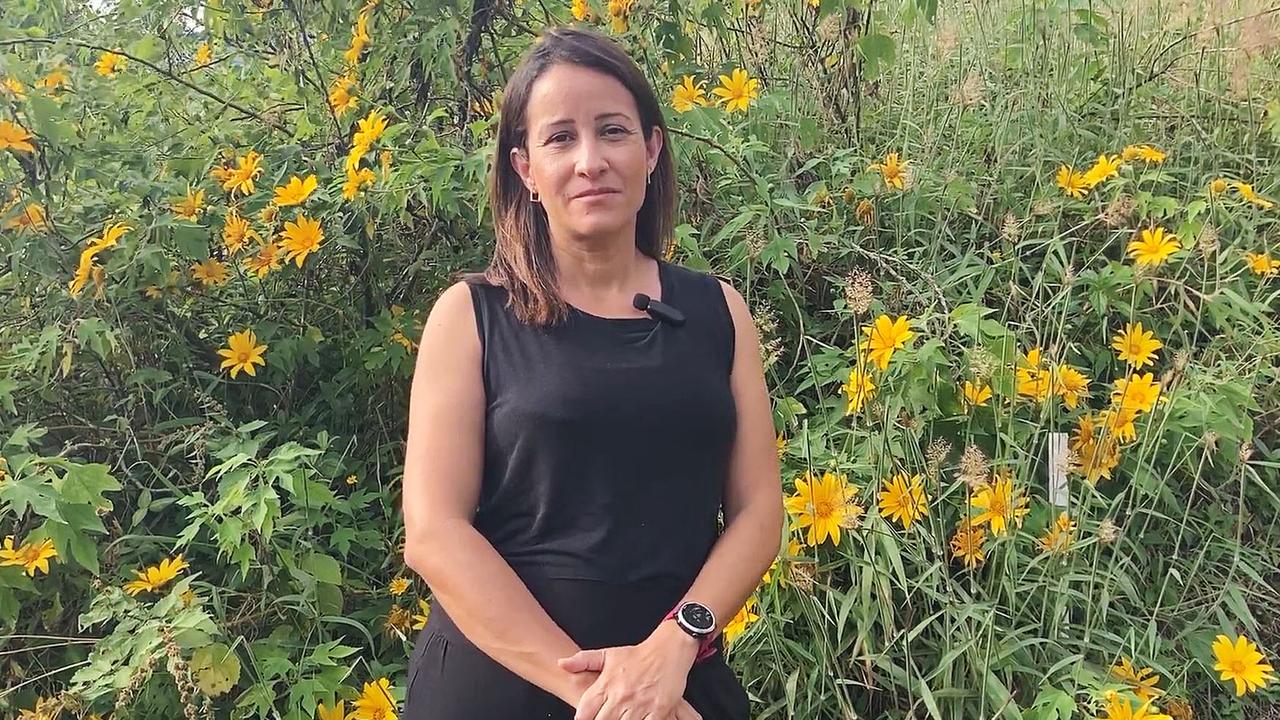 Kenia Alves at the site of her dream home which is now a vacant block of land overgrown with weeds.