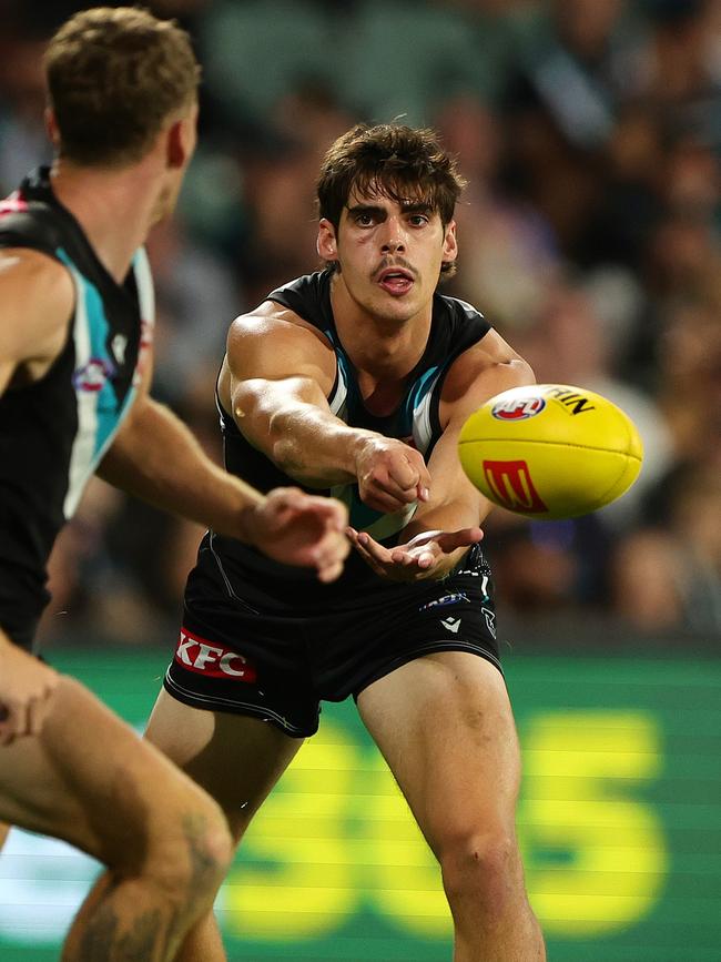 Brandon Zerk-Thatcher of the Power handpasses the ball to Kane Farrell during a game against the Demons. Picture: Sarah Reed/AFL Photos via Getty Images.