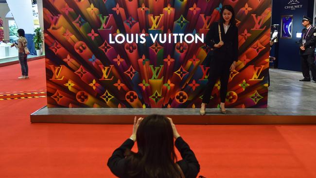 A woman poses for a picture next to a Louis Vuitton stand during an expo in Shanghai. Picture: AFP