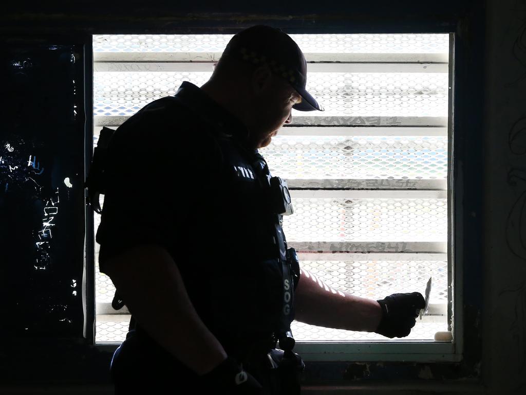 A Corrective Services officers checks the seal on a window for contraband during a raid on cells at Silverwater Jail The officers now wear body cams that record the raids. Picture: Richard Dobson