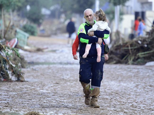 A little girl is carried by a rescue worker in Picanya, near Valencia. Picture: AFP