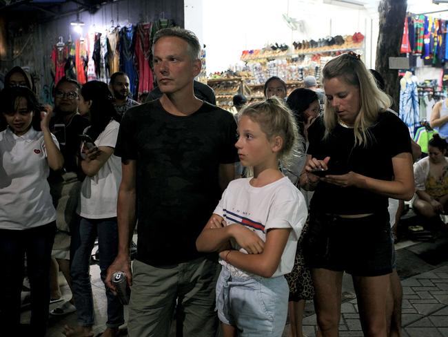 Tourists stand on the street after being evacuated from their hotel in Bali's capital Denpasar. Picture: AFP.