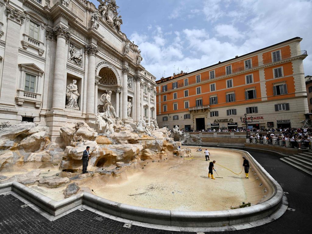 Workers clean the Trevi Fountain as tourists watch on. Picture: Alberto Pizzoli/AFP