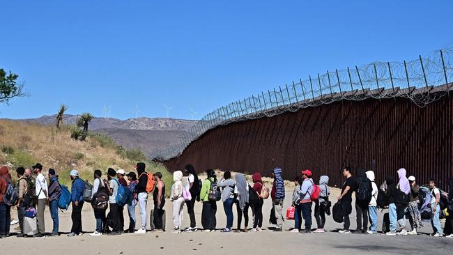 Migrants wait in line hoping for processing from Customs and Border Patrol agents after walking from Mexico into the US. Picture: AFP.