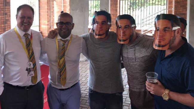 South African cricket officials Clive Eksteen (left) and Altaaf Kazi (second from left) pose with fans wearing Sonny Bill Williams masks, a slur against David Warner's wife Candice.