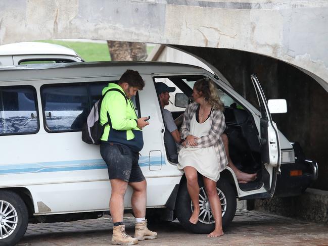 Backpackers pictured socialising with their vehicles parked under a footbridge at Bondi Beach this afternoon. Picture: David Swift