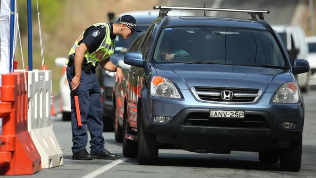 A Queensland Police officers stops a NSW registered car at a Queensland-New South Wales border checkpoint. Picture: Scott Powick