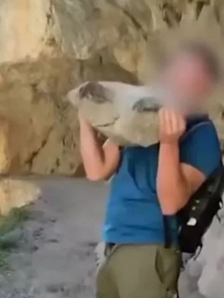 The tourist is seen casting the heavy rock in northern Spain's Picos de Europa National Park.