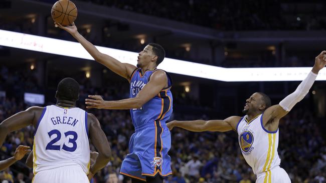 Oklahoma City Thunder guard Andre Roberson lays up a shot between Golden State Warriors' Draymond Green (23) and Andre Iguodala.