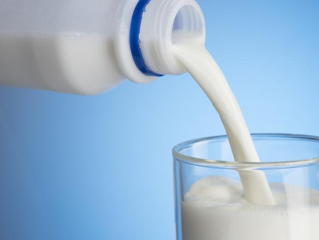 Pouring Milk Into Glass on Blue Background