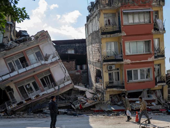 People walk next to damaged buildings in the Antakia historical city of Hatay. Picture: AFP